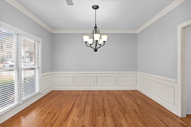 unfurnished room with a notable chandelier, hardwood / wood-style flooring, and ornamental molding