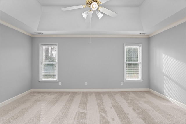 carpeted spare room featuring lofted ceiling, a tray ceiling, ornamental molding, and ceiling fan