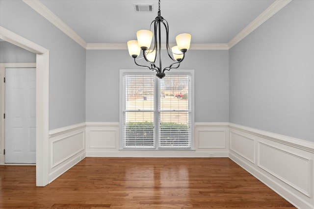 unfurnished dining area with hardwood / wood-style floors, crown molding, and a chandelier