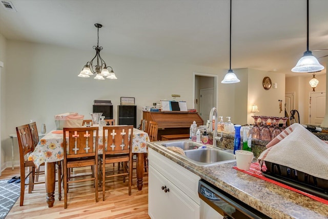 kitchen with white cabinets, sink, hanging light fixtures, and an inviting chandelier