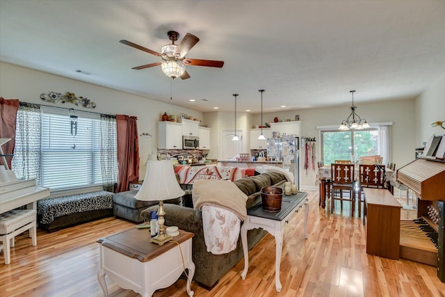 living room with light hardwood / wood-style flooring and ceiling fan with notable chandelier