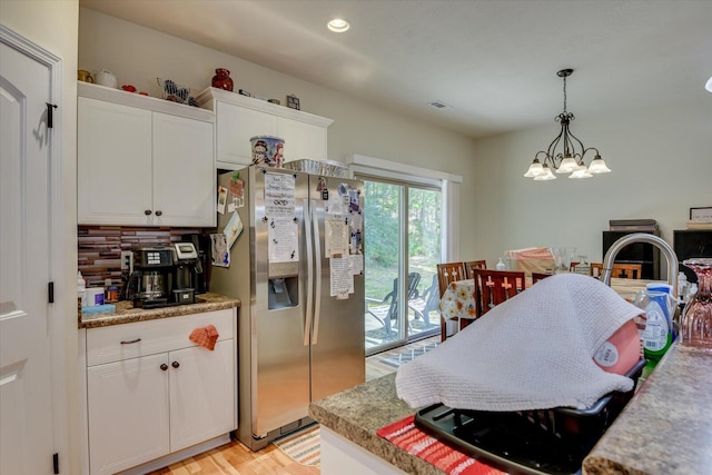 kitchen featuring stainless steel refrigerator with ice dispenser, backsplash, decorative light fixtures, a notable chandelier, and white cabinets