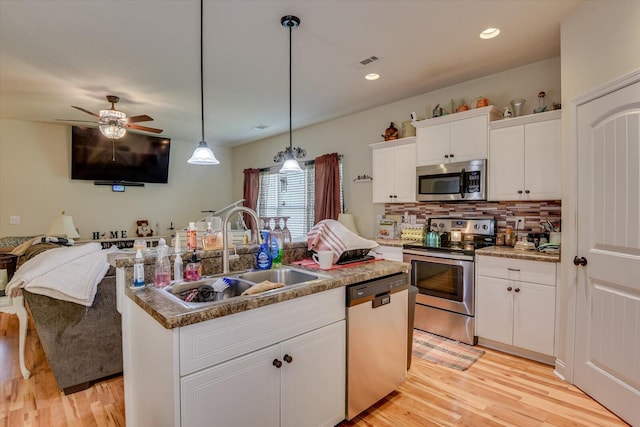 kitchen featuring appliances with stainless steel finishes, sink, pendant lighting, white cabinetry, and an island with sink