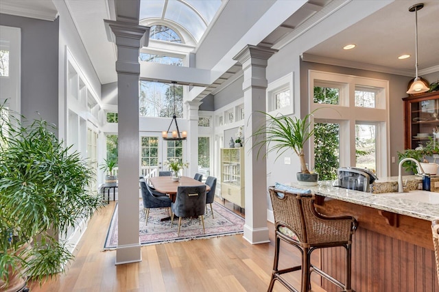 sunroom / solarium featuring a chandelier, decorative columns, and a sink