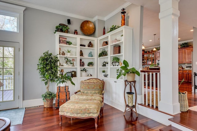 living area with dark wood-style flooring, visible vents, crown molding, and ornate columns