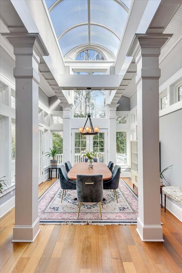 dining room with a chandelier, plenty of natural light, hardwood / wood-style floors, and ornate columns