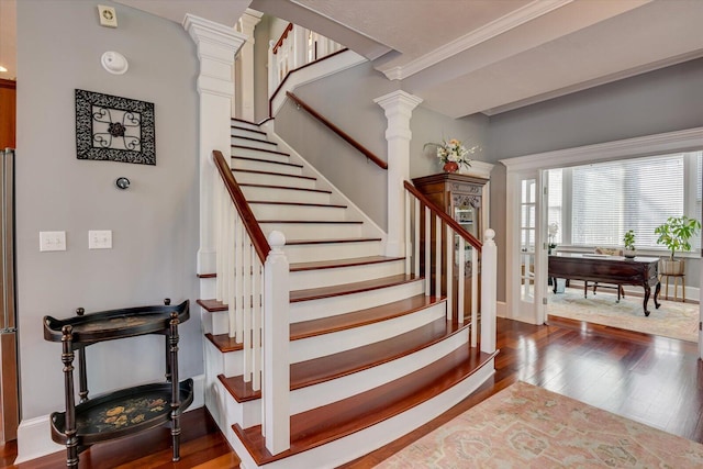 stairs featuring crown molding, hardwood / wood-style floors, decorative columns, and baseboards