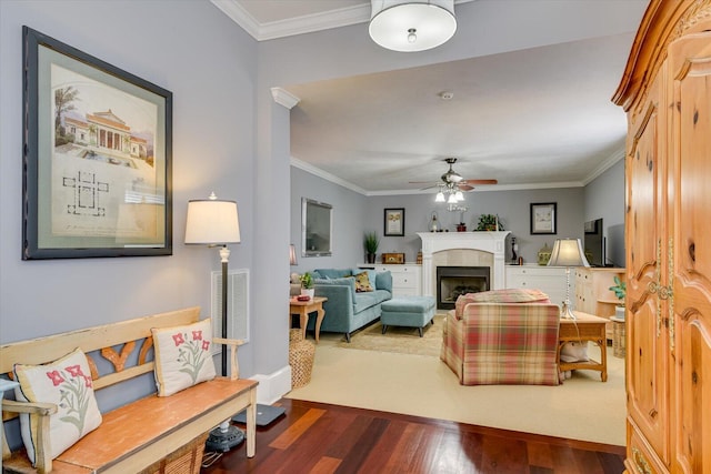 living room with ceiling fan, a tile fireplace, wood finished floors, visible vents, and crown molding