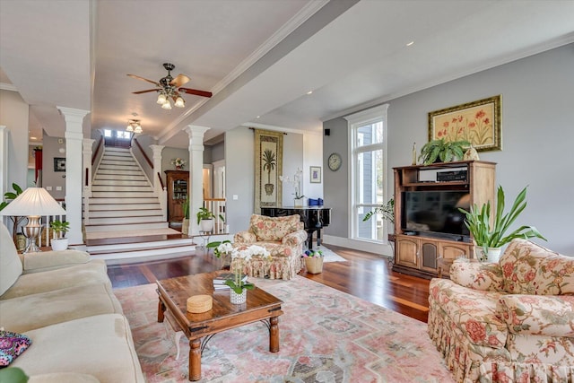 living room with ornate columns, stairway, crown molding, and wood finished floors