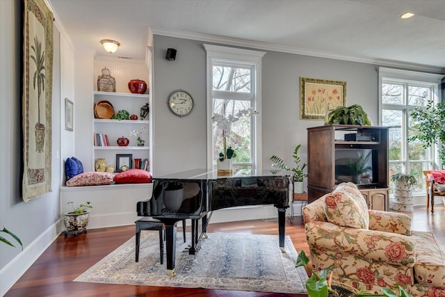 living area with built in shelves, wood finished floors, and crown molding