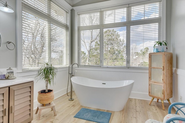 bathroom featuring a soaking tub, plenty of natural light, and wood finished floors