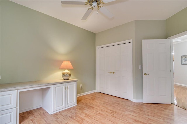 unfurnished bedroom with built in desk, a closet, ceiling fan, and light hardwood / wood-style floors