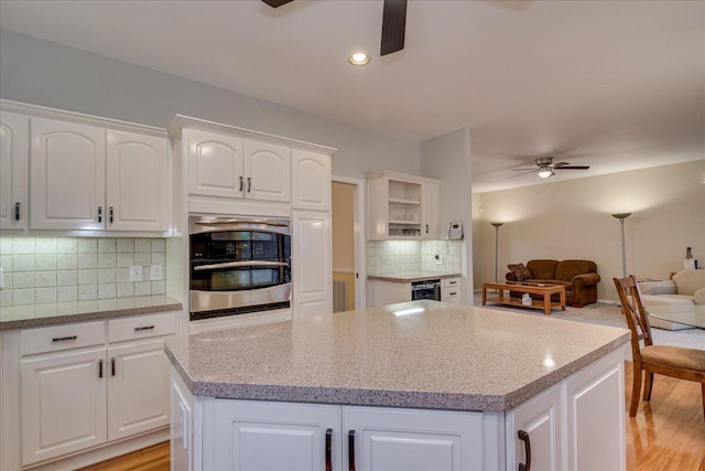 kitchen with backsplash, white cabinetry, and stainless steel oven