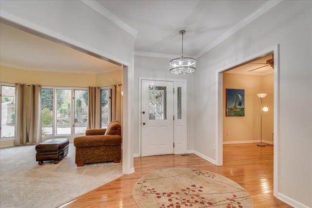 foyer entrance featuring crown molding, light hardwood / wood-style floors, and ceiling fan with notable chandelier