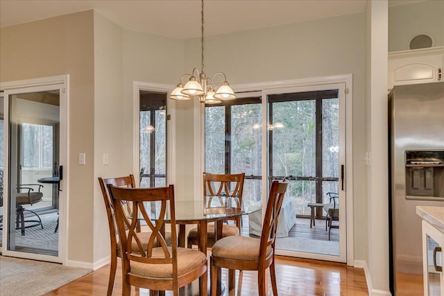 dining space featuring a healthy amount of sunlight, light hardwood / wood-style flooring, and a chandelier