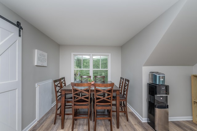 dining room with wood finished floors, baseboards, and a barn door