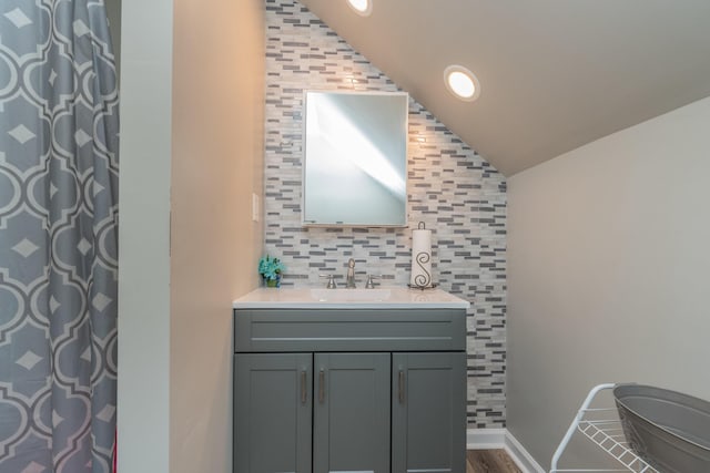 bathroom with a shower with shower curtain, toilet, vaulted ceiling, vanity, and backsplash