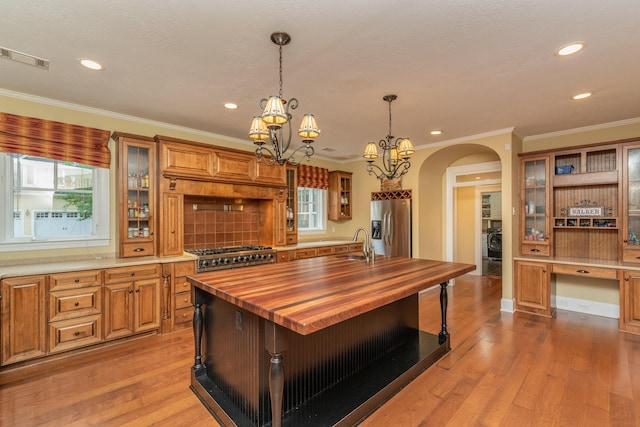 kitchen with arched walkways, an inviting chandelier, butcher block counters, stainless steel fridge with ice dispenser, and wood-type flooring