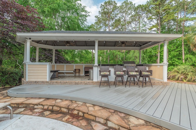 deck with a ceiling fan, a gazebo, and exterior bar