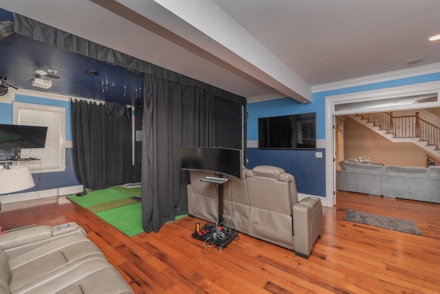 living room with wood finished floors, stairs, ornamental molding, and golf simulator