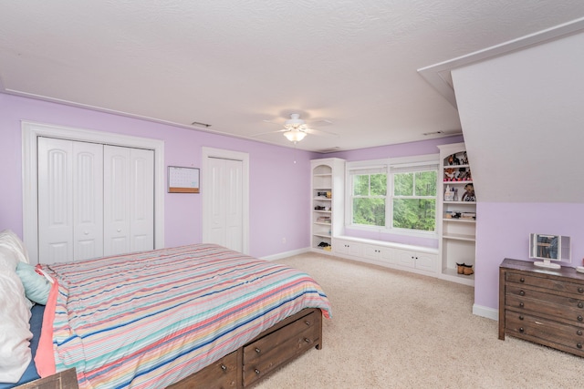 carpeted bedroom featuring ceiling fan, multiple closets, and baseboards