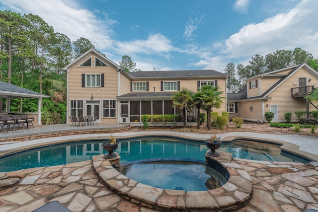 view of pool with outdoor dining space, a deck, a pool with connected hot tub, and a sunroom