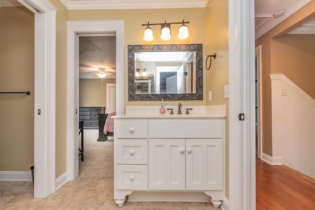 bathroom featuring ceiling fan, vanity, crown molding, and baseboards