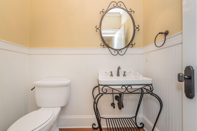 half bathroom featuring toilet and a wainscoted wall