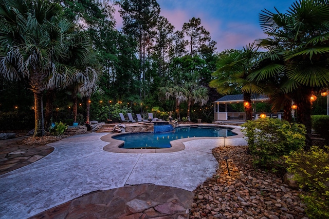 pool at dusk with a patio, a gazebo, an in ground hot tub, and an outdoor pool