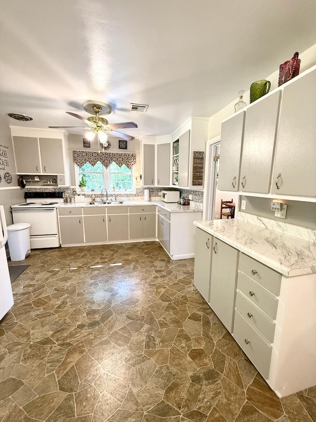 kitchen with a sink, visible vents, a ceiling fan, white electric stove, and stone flooring
