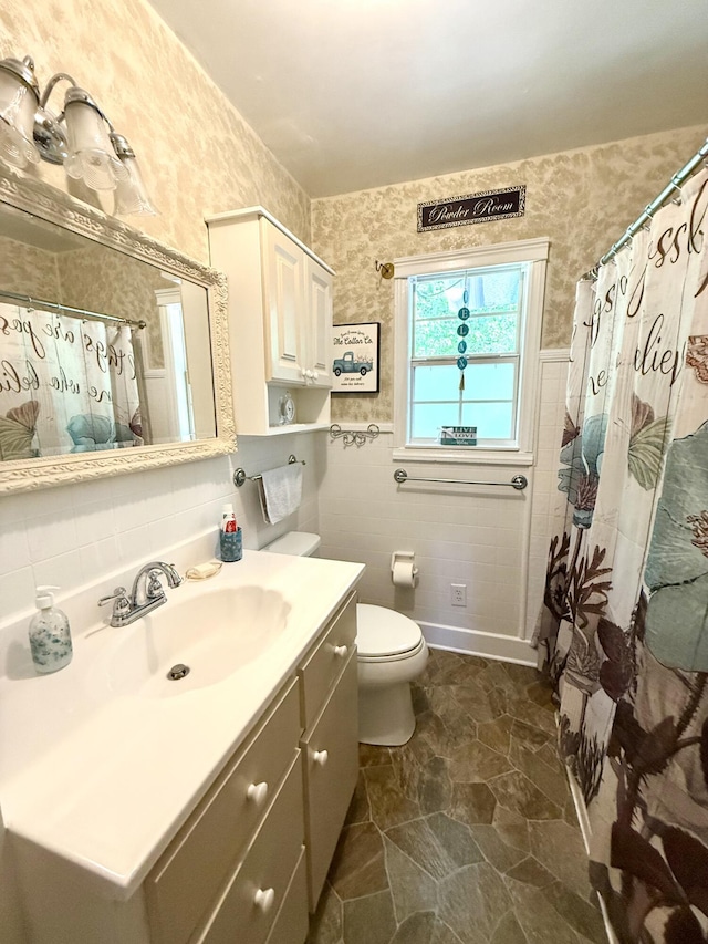 full bathroom with vanity, toilet, tile walls, and wallpapered walls
