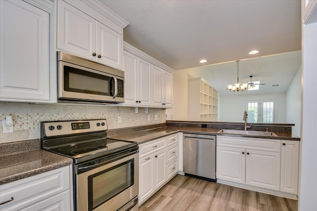 kitchen with appliances with stainless steel finishes, a sink, a chandelier, white cabinetry, and light wood-type flooring