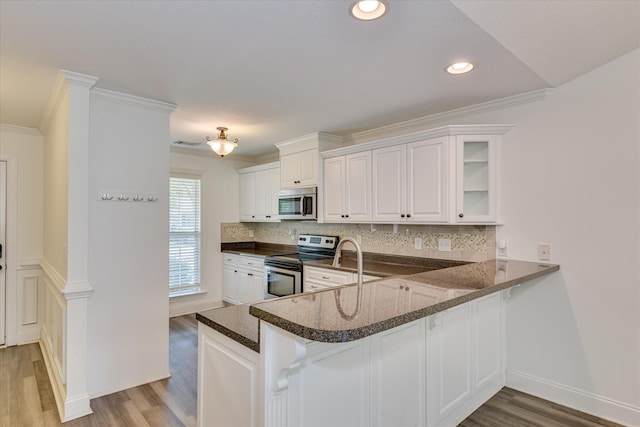 kitchen featuring appliances with stainless steel finishes, light wood-type flooring, backsplash, white cabinets, and ornamental molding