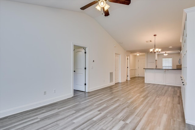 unfurnished living room featuring lofted ceiling, a ceiling fan, a chandelier, light wood finished floors, and baseboards