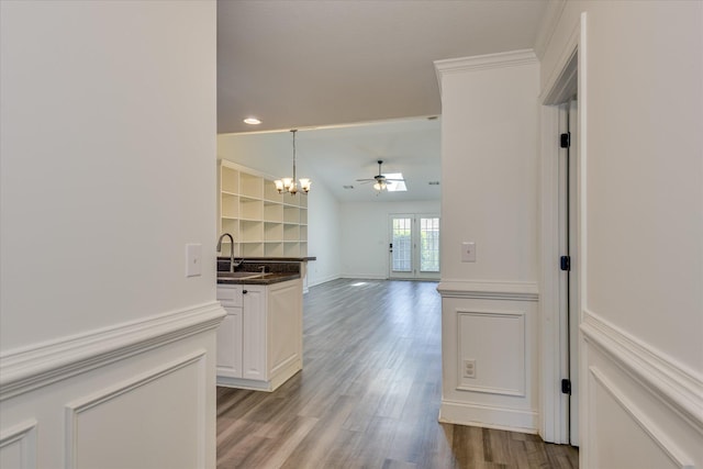 kitchen with dark countertops, a sink, a chandelier, wood finished floors, and ceiling fan
