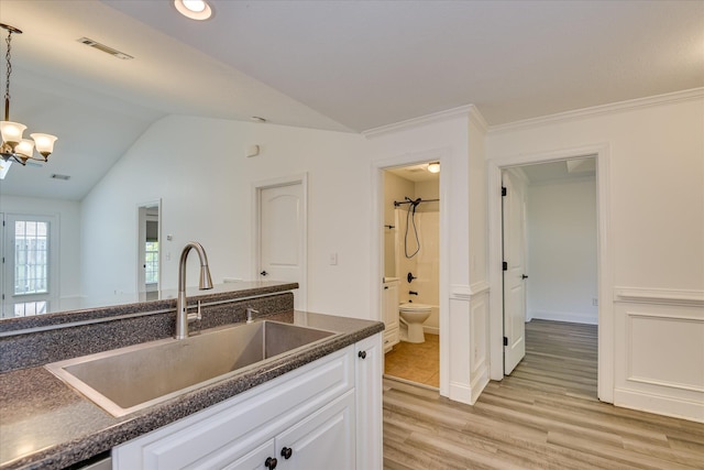 kitchen with a sink, dark countertops, light wood finished floors, a chandelier, and white cabinetry