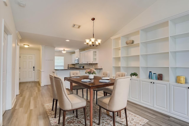 dining space with a chandelier, light wood finished floors, and lofted ceiling