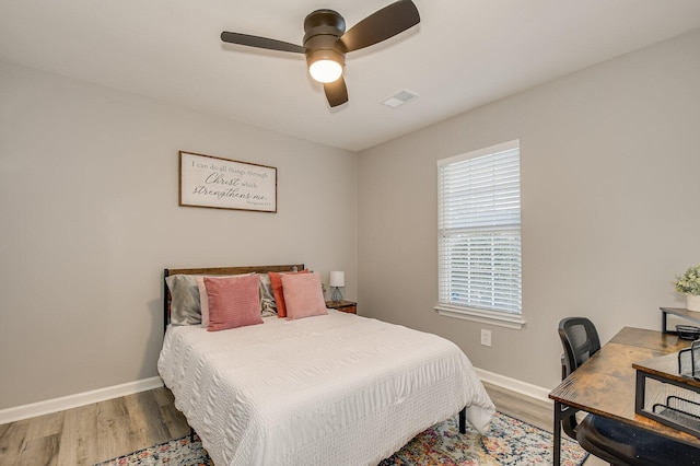 bedroom with ceiling fan, wood finished floors, visible vents, and baseboards