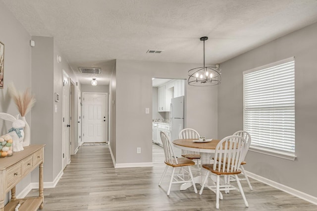 dining space featuring light wood-type flooring, baseboards, and visible vents