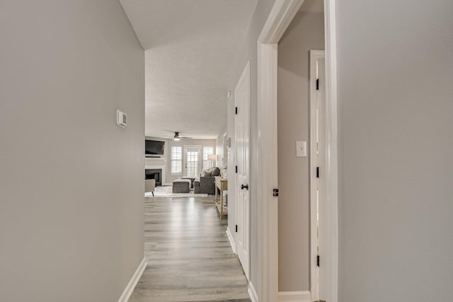 hallway featuring light wood-style floors and baseboards