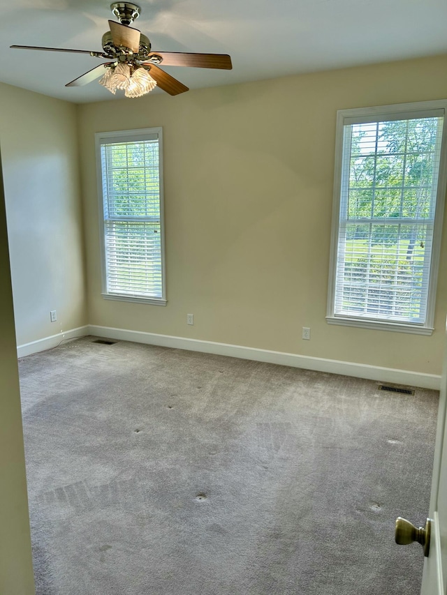 carpeted spare room with baseboards, a ceiling fan, and visible vents