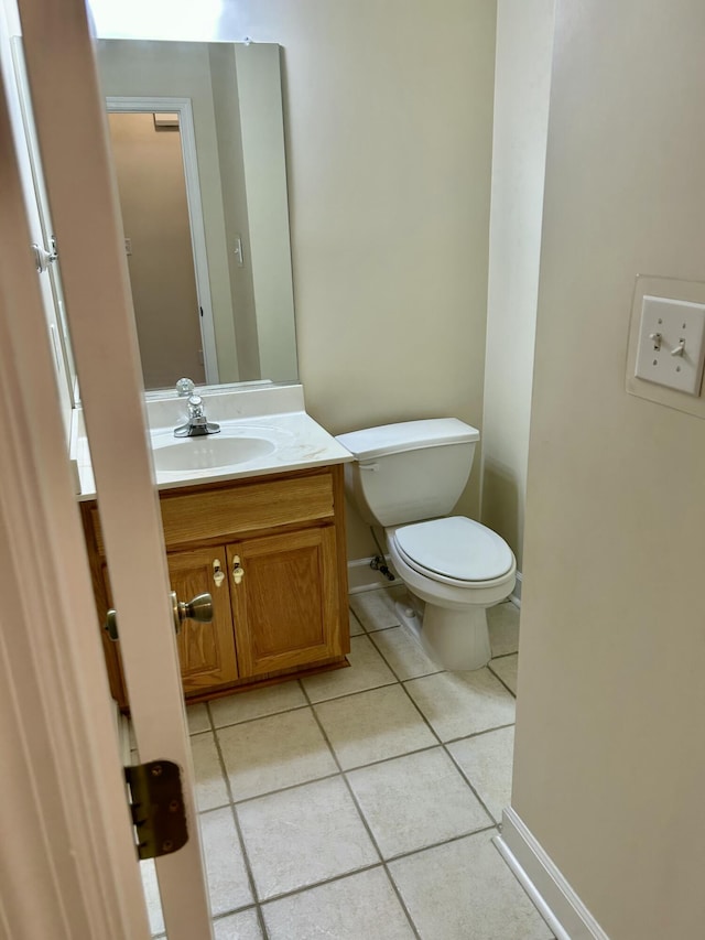 half bathroom with toilet, baseboards, tile patterned flooring, and vanity