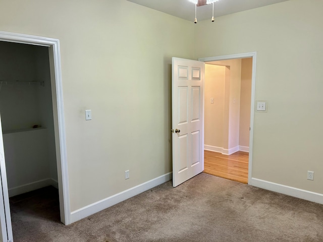 unfurnished bedroom with carpet floors, baseboards, and a spacious closet