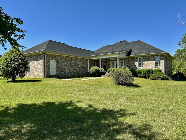 rear view of house featuring a lawn and brick siding
