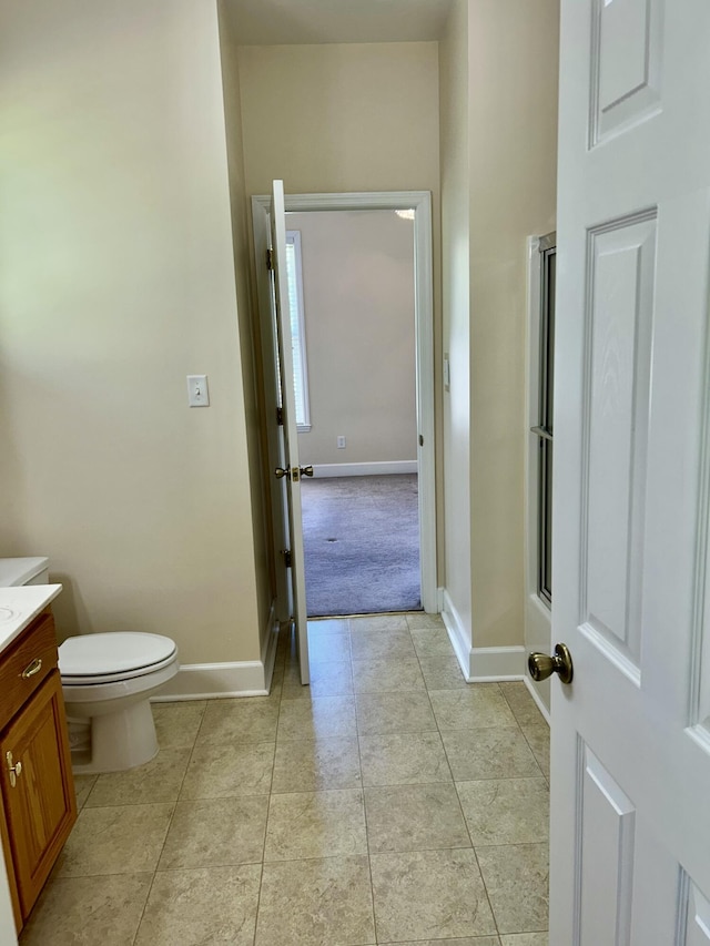 full bath with tile patterned flooring, a shower with shower door, vanity, baseboards, and toilet