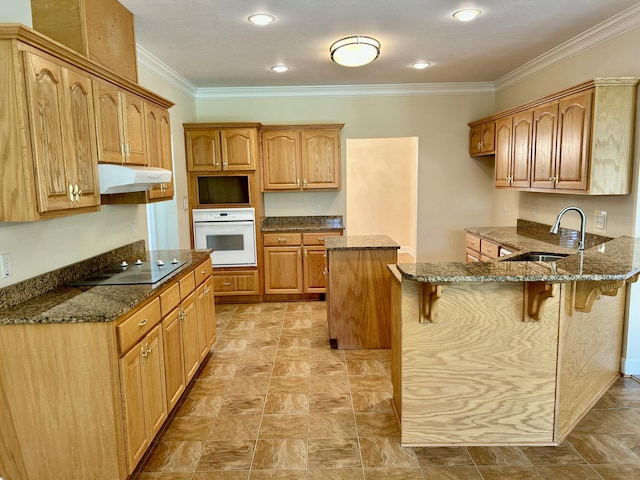 kitchen featuring a peninsula, electric cooktop, a kitchen bar, white oven, and a sink