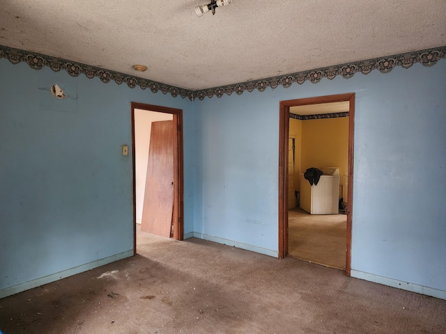 unfurnished room with washer / clothes dryer, baseboards, and a textured ceiling