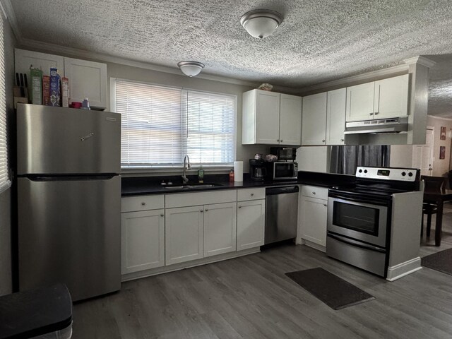 2402 Wheeless Rd, Augusta, GA 30906 - kitchen with stainless steel appliances, under cabinet range hood, a textured ceiling, dark countertops, and white cabinetry