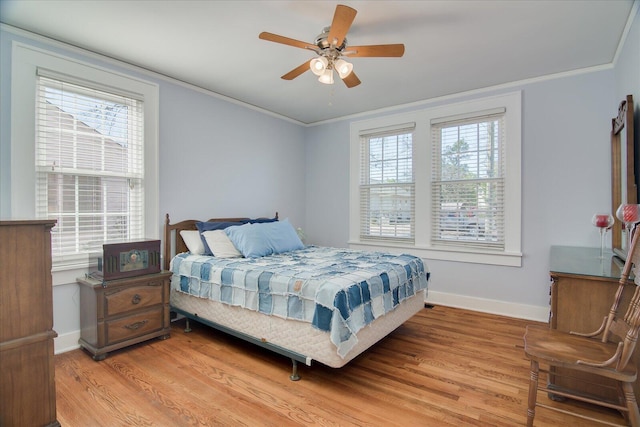 bedroom featuring light wood-style flooring, ornamental molding, ceiling fan, and baseboards