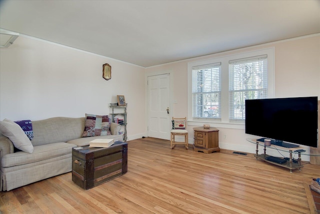 living area with light wood-type flooring, crown molding, and baseboards